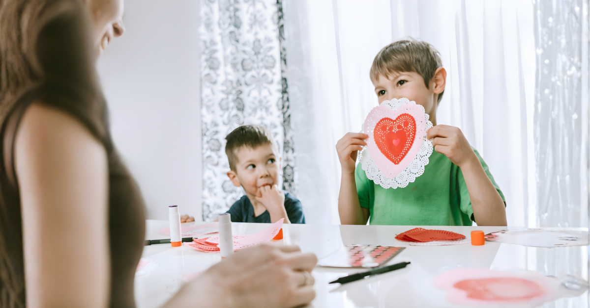 Child showing a handmade Valentine card to a single parent at the table